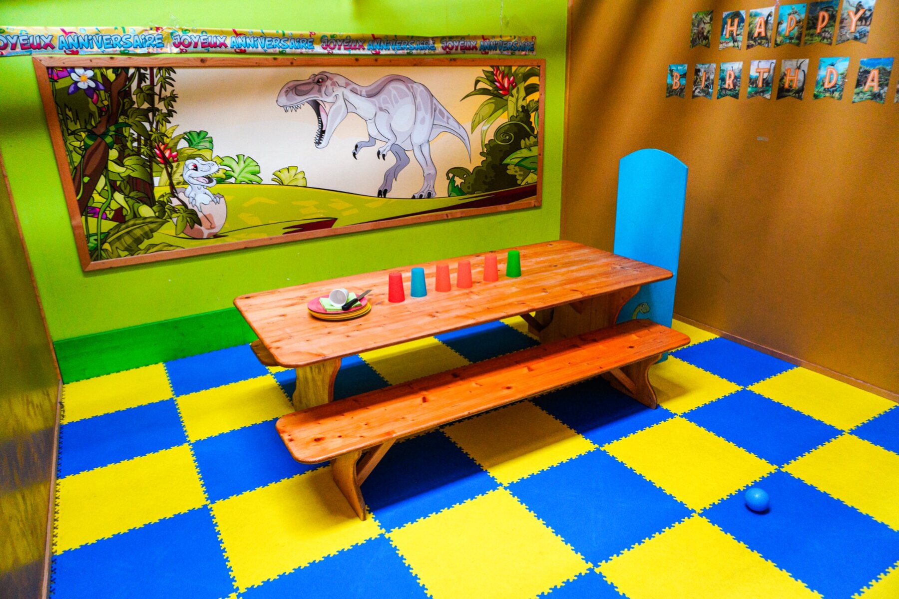 Cabane anniversaire avec table dressée, chaises colorées et décor de dinosaures