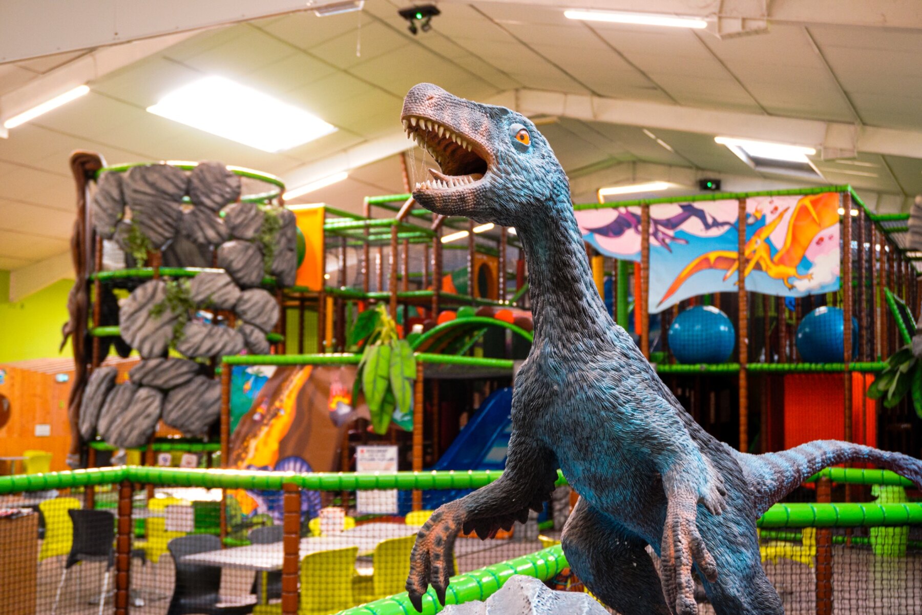 Dinosaure devant la grande structure de jeux de la Zone Dino à Fun City Fréjus