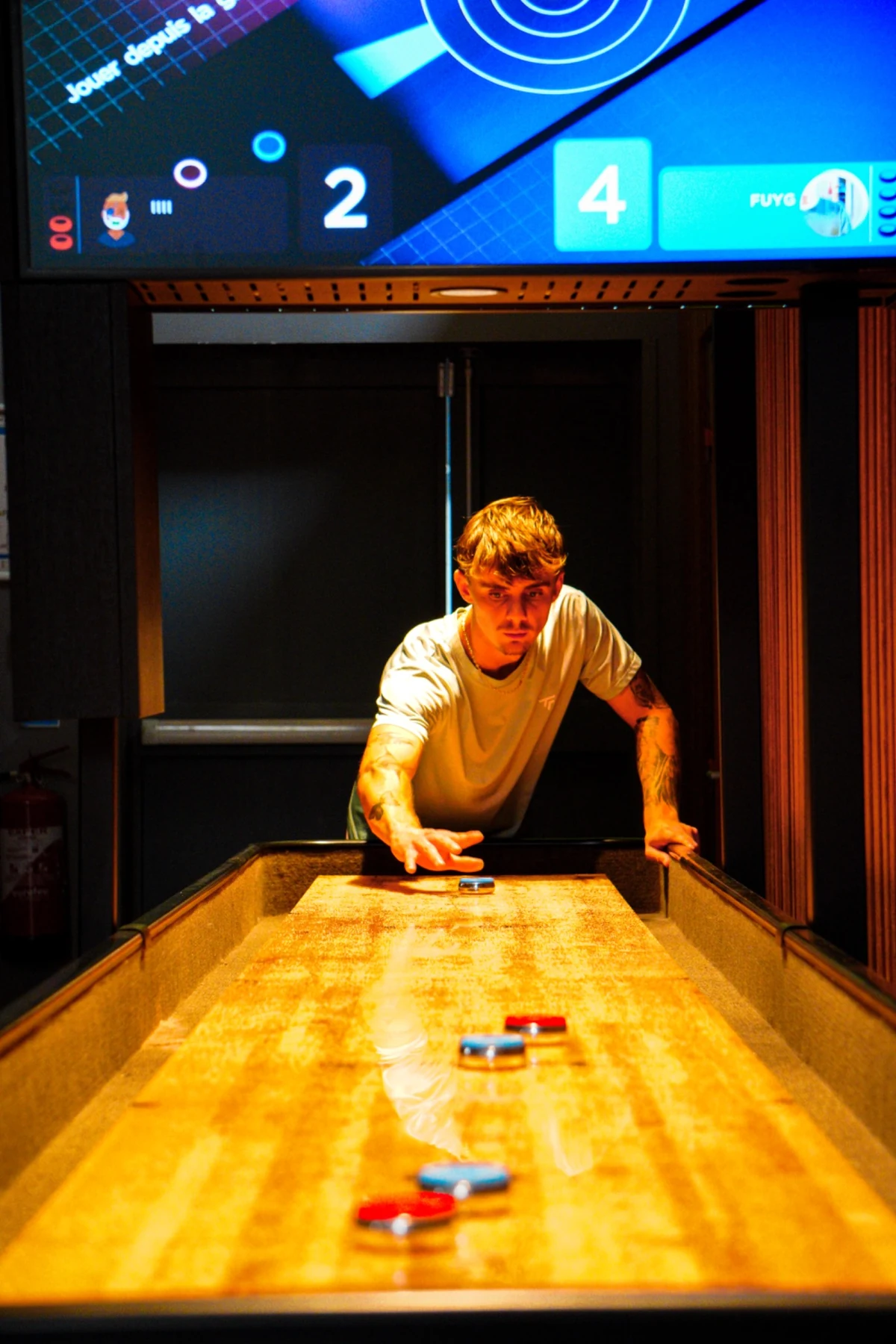 Joueur faisant glisser un palet sur la table de shuffleboard à Fun City Fréjus