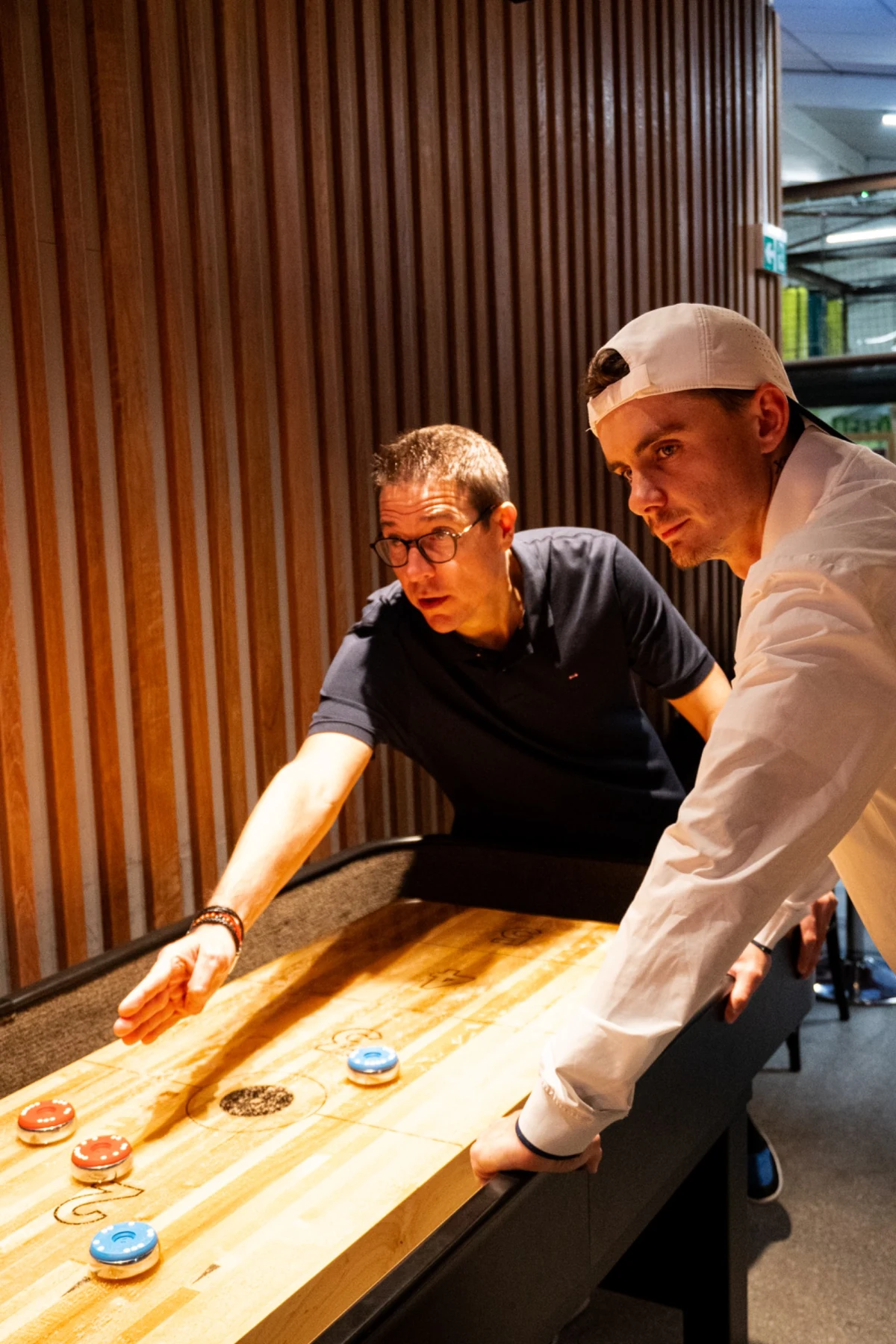 Deux joueurs concentrés autour de la table de shuffleboard à Fun City Fréjus